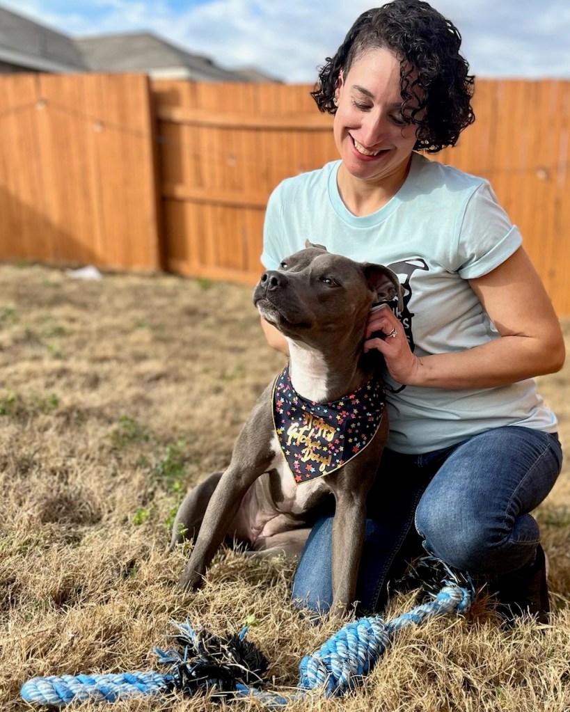Photo of Cristy in a "Show Me Your Pitties" shirt and her dog Ladybird to celebrate their birthday and gotcha day