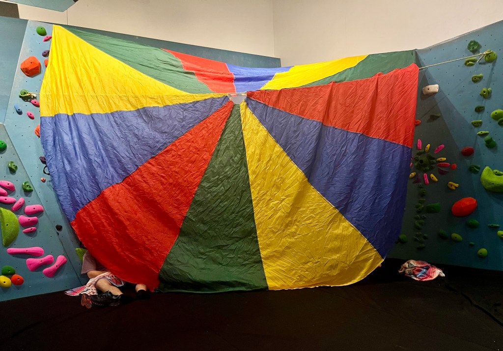 DIY tent made from giant parachute inside youth bouldering gym area